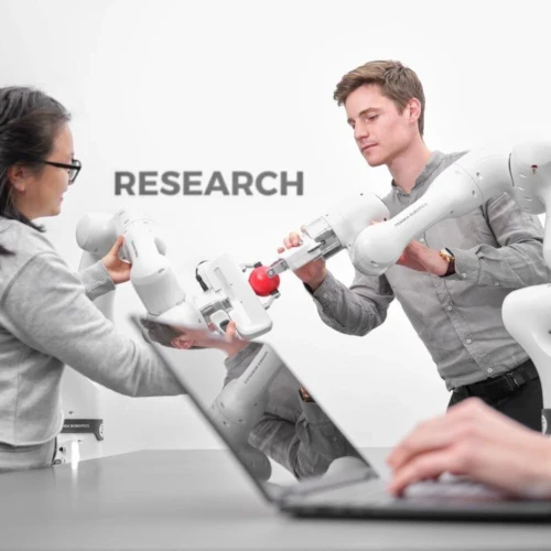 Manipulacja obiektem za pomocą ramion robotów Franka Research 3 w środowisku laboratoryjnym. Interakcja dwóch osób z ramionami robota Franka podczas przekazywania piłki w laboratorium badawczym